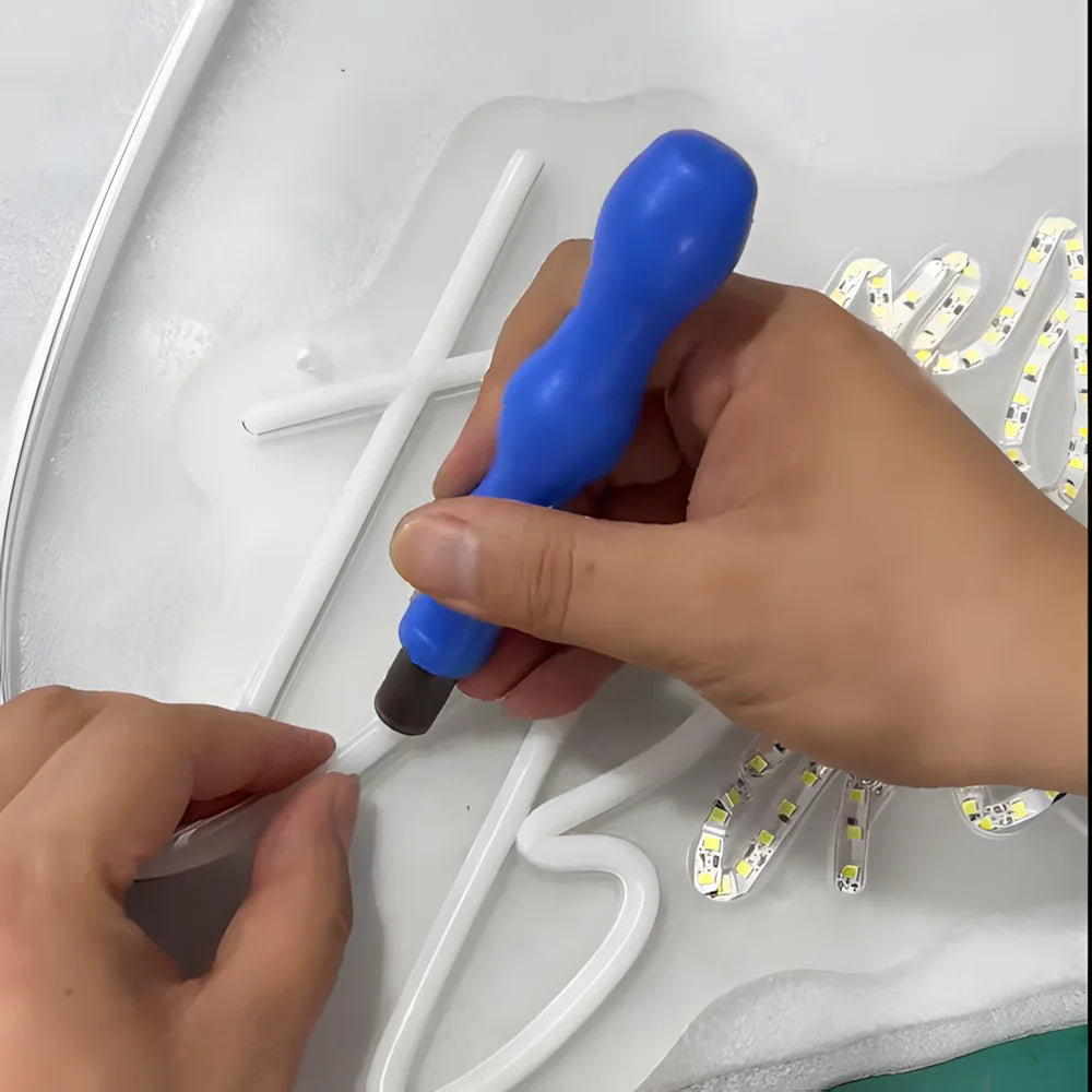 Close-up of silicone tubing being pressed into a neon sign by hand.
